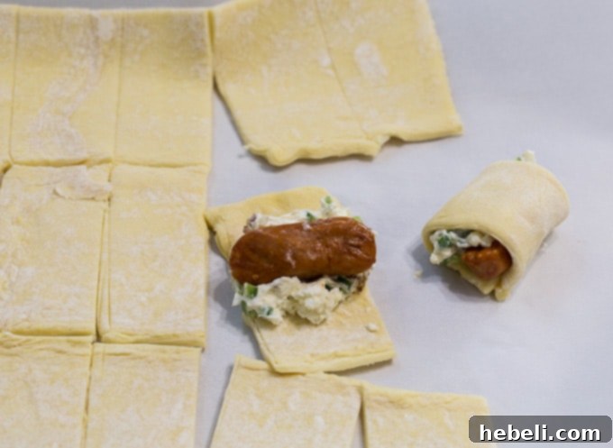 Spicy Piggy Poppers 5 Raw Jalapeno Popper Pigs in a Blanket ready for the oven, topped with sliced jalapeños.