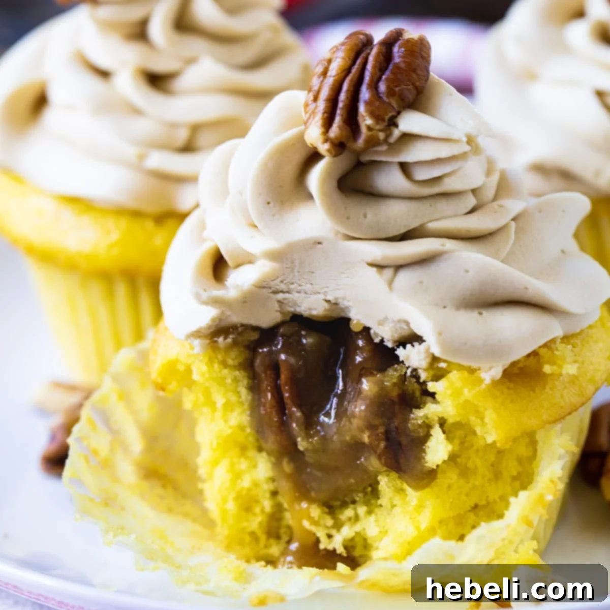 A delicious Pecan Pie Cupcake with a bite taken out, revealing the gooey pecan pie filling inside, topped with fluffy brown sugar buttercream.