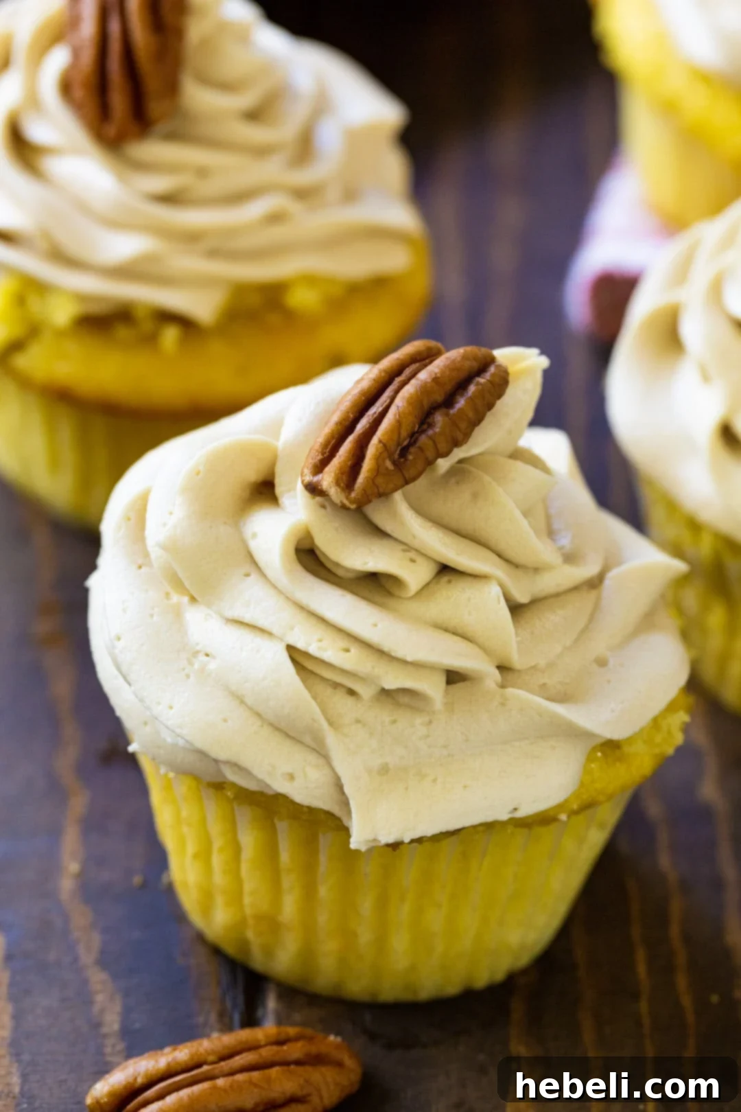 Two beautifully frosted Pecan Pie Cupcakes, garnished with whole pecans, showcasing the rich brown sugar buttercream.