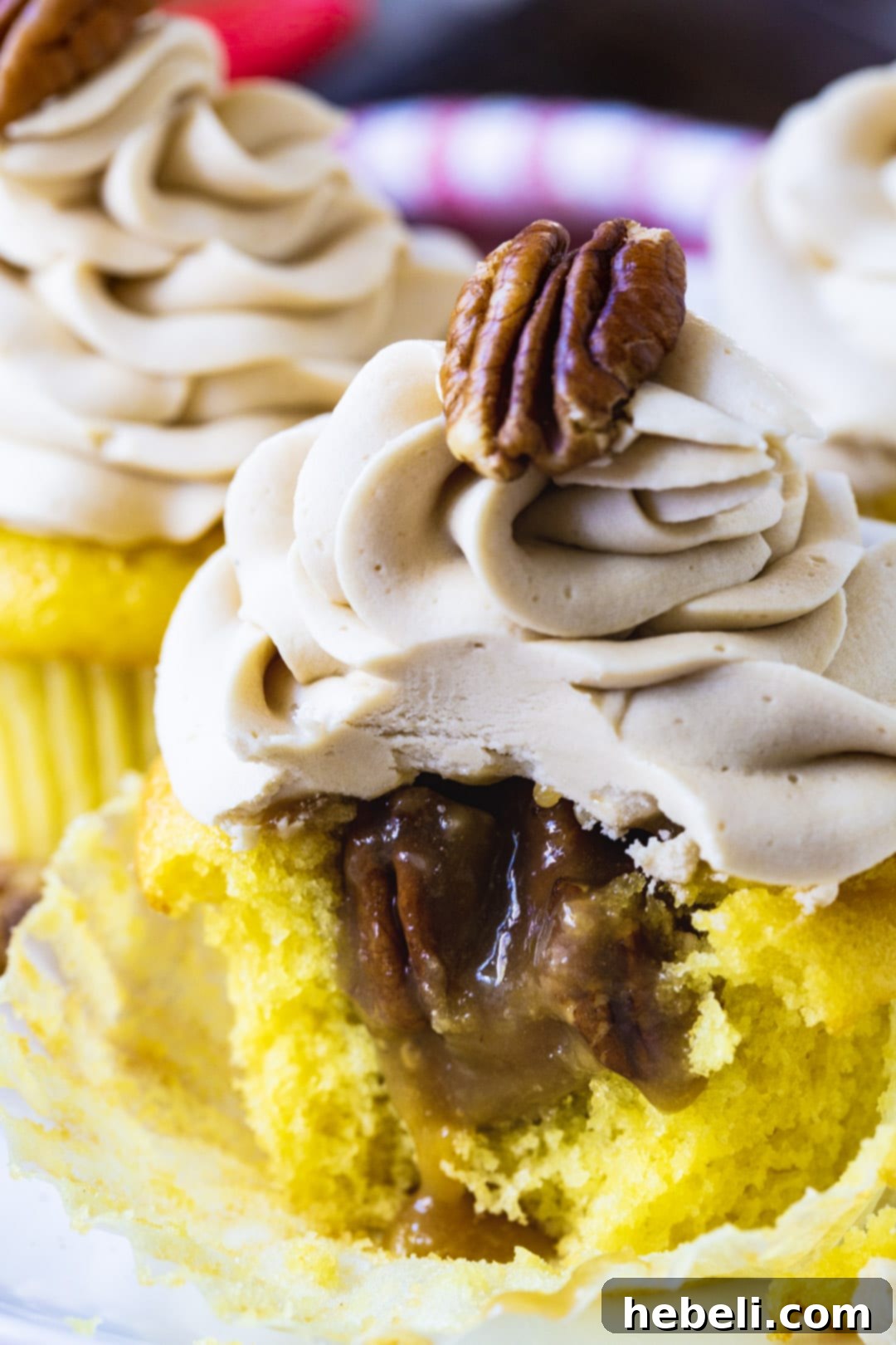 A pecan pie cupcake with a slice removed to reveal the luscious, hidden pecan pie filling within.
