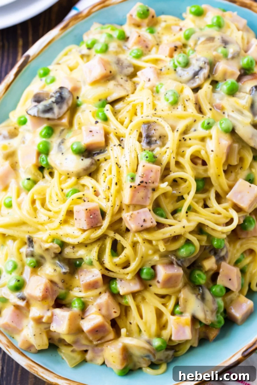 A generous portion of Ham Tetrazzini served in a vibrant blue oval casserole dish, highlighting its creamy, golden-brown surface and rich ingredients.