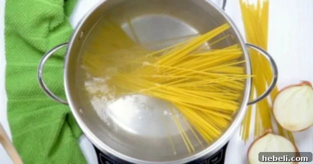 A pot of spaghetti being cooked in boiling salted water on a stovetop, preparing it for the Tetrazzini dish.