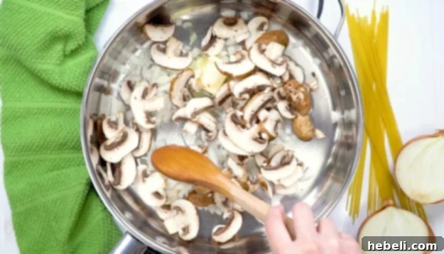 Diced onions and sliced mushrooms sizzling in melted butter within a large skillet, releasing their aromatic flavors.