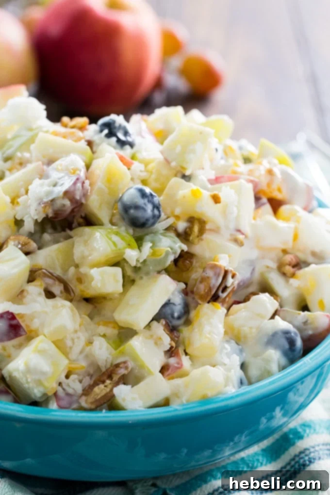 Silky Fruit Ambrosia 5 A large serving of Creamy Fruit Salad in a white bowl, ready for a potluck, featuring various fruits and a rich dressing.