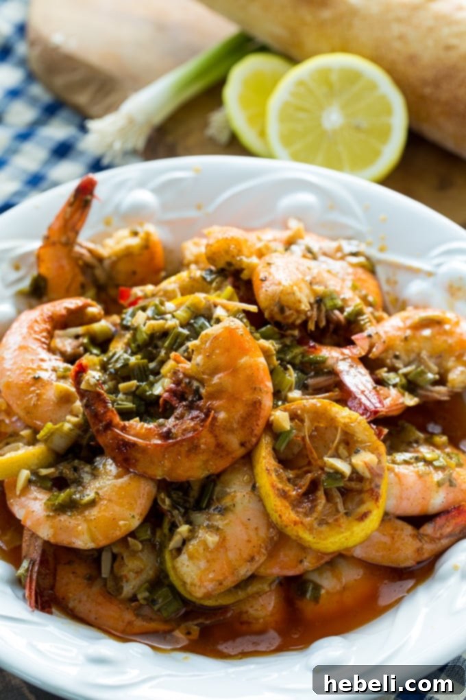 New Orleans-Style BBQ Shrimp served in a bowl with lemon wedges and French bread on the side