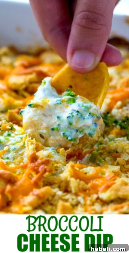 Hand scooping creamy, hot broccoli cheese dip with a Frito chip, highlighting the inviting texture and readiness to eat.