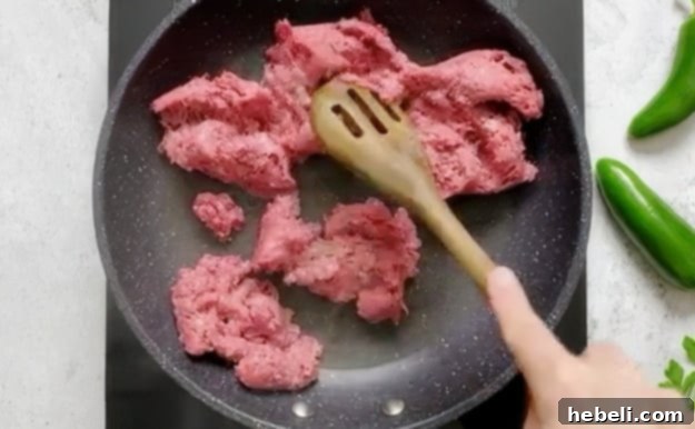 Browning ground beef in a skillet for queso