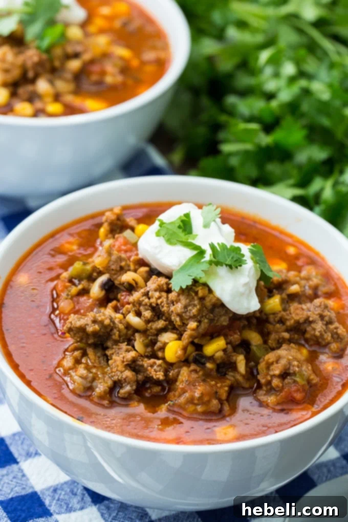 A bowl of Black-Eyed Pea and Sausage Chili with corn kernels visible, ready to be served.