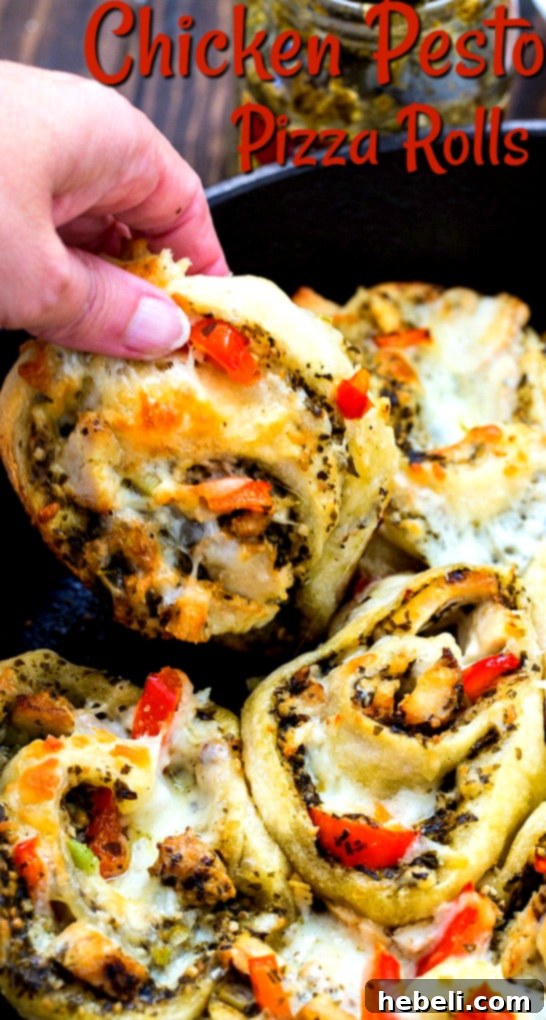 Close-up of a hand picking up a freshly baked Chicken Pesto Pizza Roll from a cast iron pan, showing the flaky crust and melted cheese.
