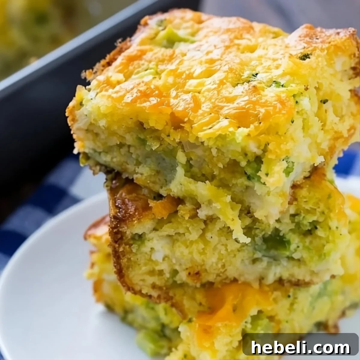 Golden Cheesy Broccoli Cornbread 2 Cheesy Broccoli Cornbread stacked on a plate, featuring a golden crust and visible broccoli florets.