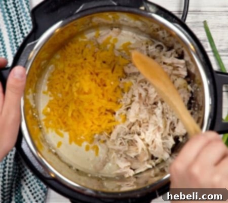 Addictive Instant Pot Chicken 8 Folding shredded chicken and cheddar cheese into the thickened, creamy sauce in the Instant Pot.