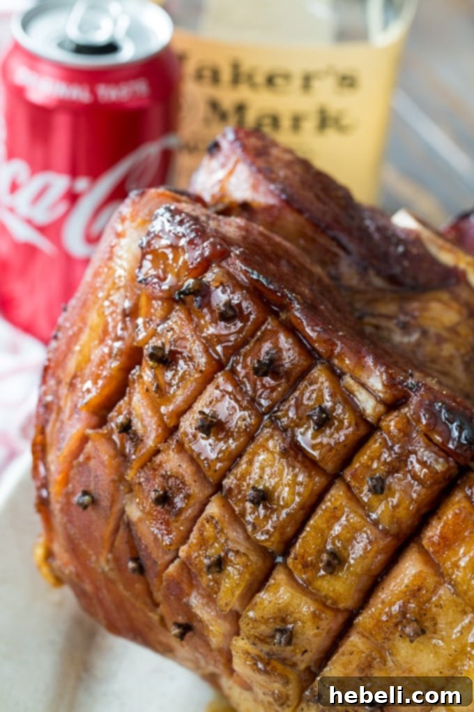 Bourbon and Coke Glazed Ham recipe in a large pot with Coca-Cola and onion simmering on the stove