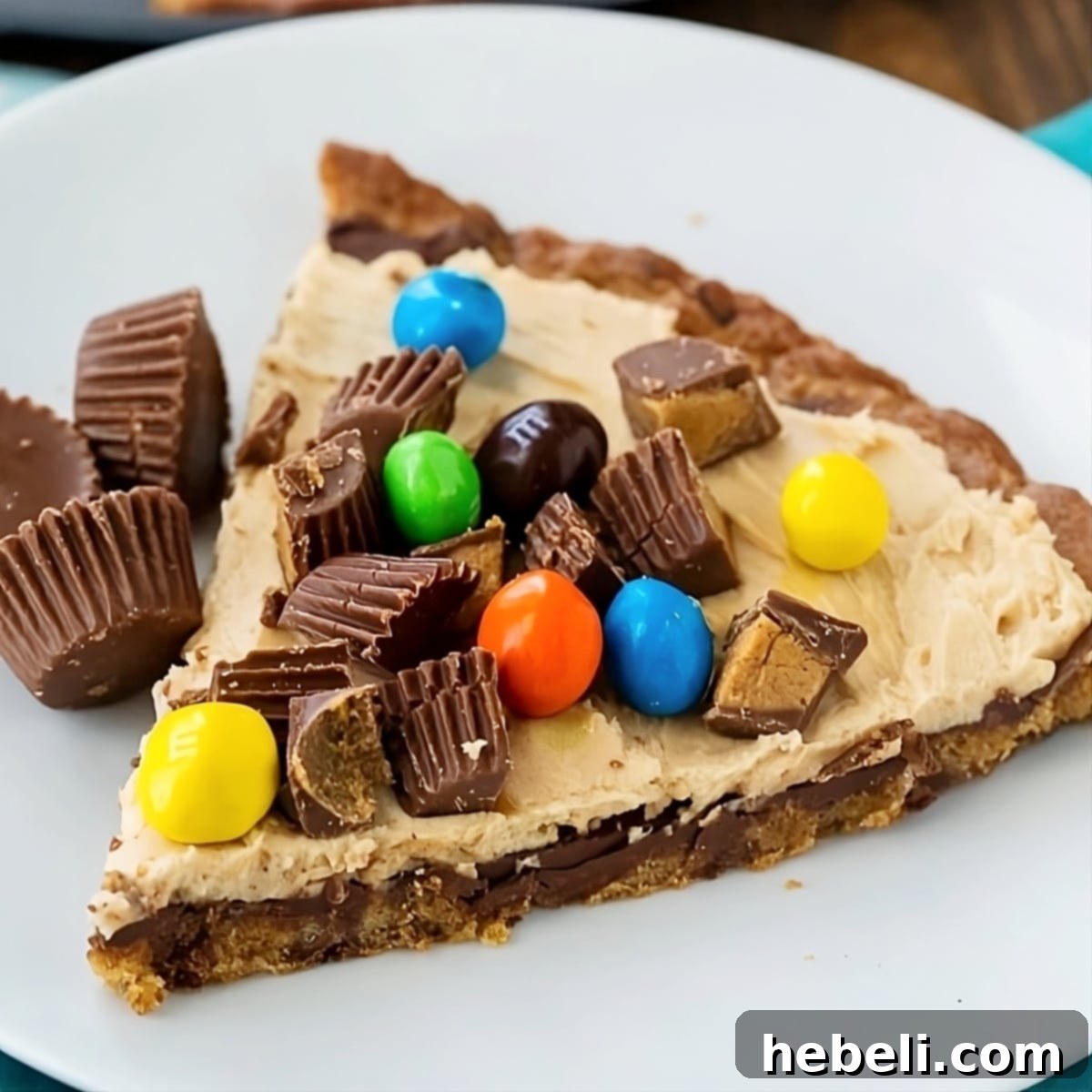 Decadent Peanut Butter Cup Pizza 2 Slice of Peanut Butter Cup Dessert Pizza on a plate, showcasing layers and toppings.