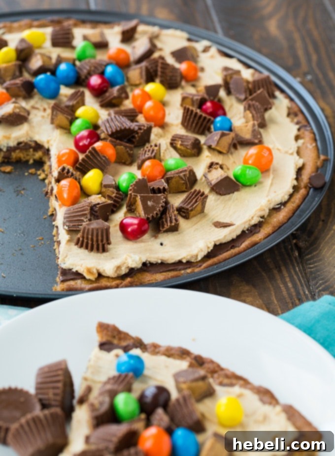 Decadent Peanut Butter Cup Pizza 5 A slice of Peanut Butter Cup Dessert Pizza on a white plate, ready to be enjoyed.