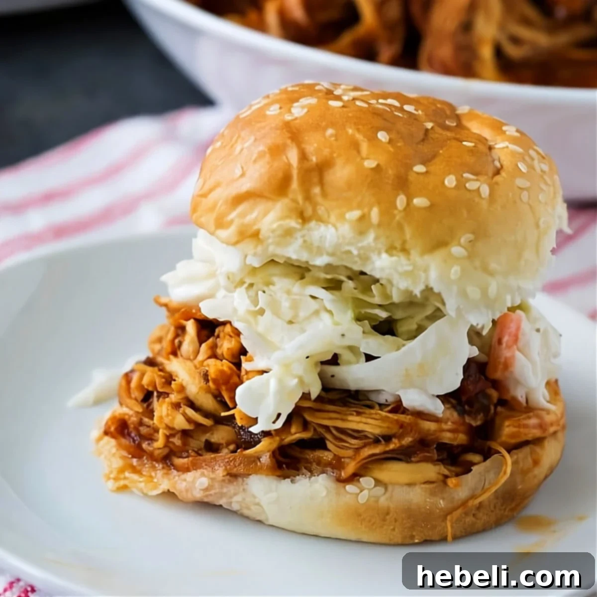 Smoky Slow Cooker Pulled Chicken 2 Chipotle Pulled Chicken with coleslaw on a bun, showcasing a delicious serving suggestion.