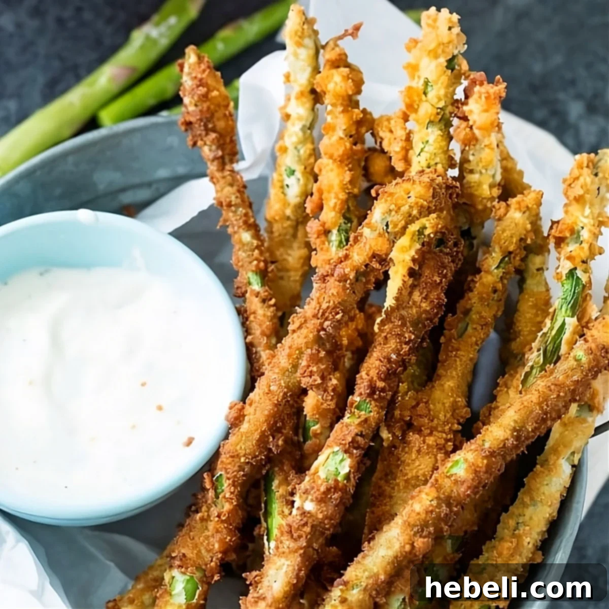Crispy Fried Asparagus in a rustic basket, served alongside a bowl of creamy ranch dressing for dipping. Perfect for a spring appetizer.