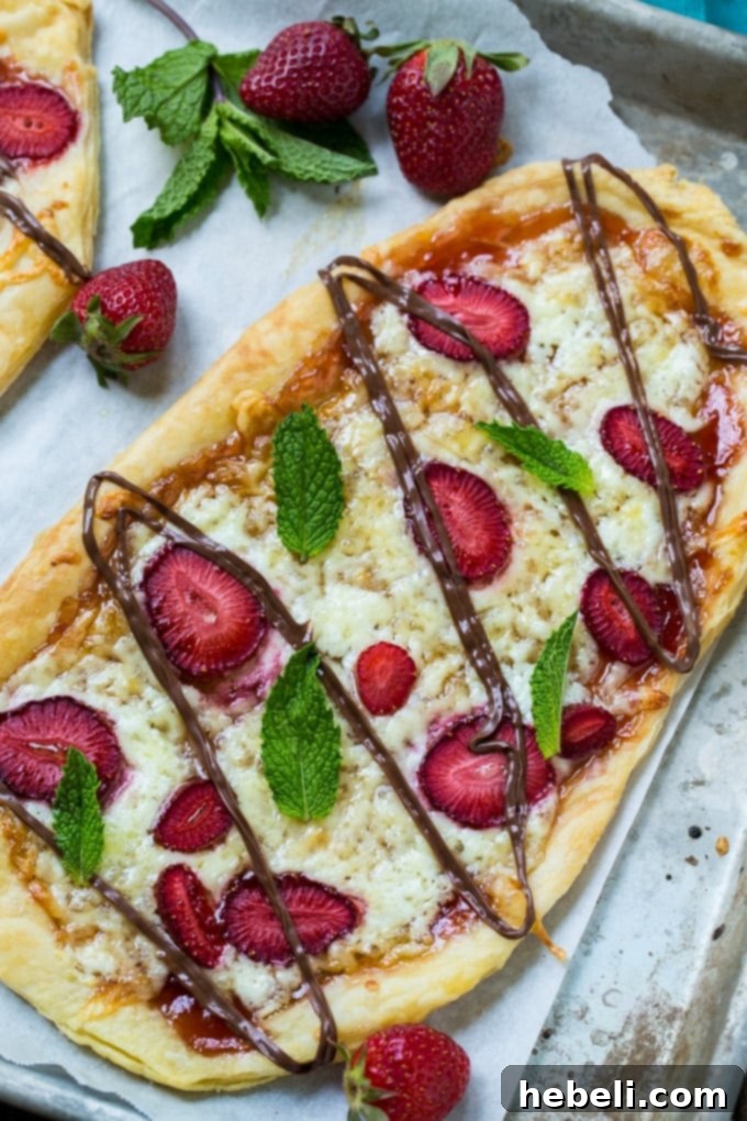Strawberry Nutella Dessert Pizza baking on a puff pastry crust, partially cooked