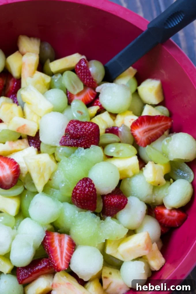 Amaretto Kissed Fruit Medley 3 Amaretto Fruit Salad with pineapple, strawberries, and honeydew in a clear bowl.