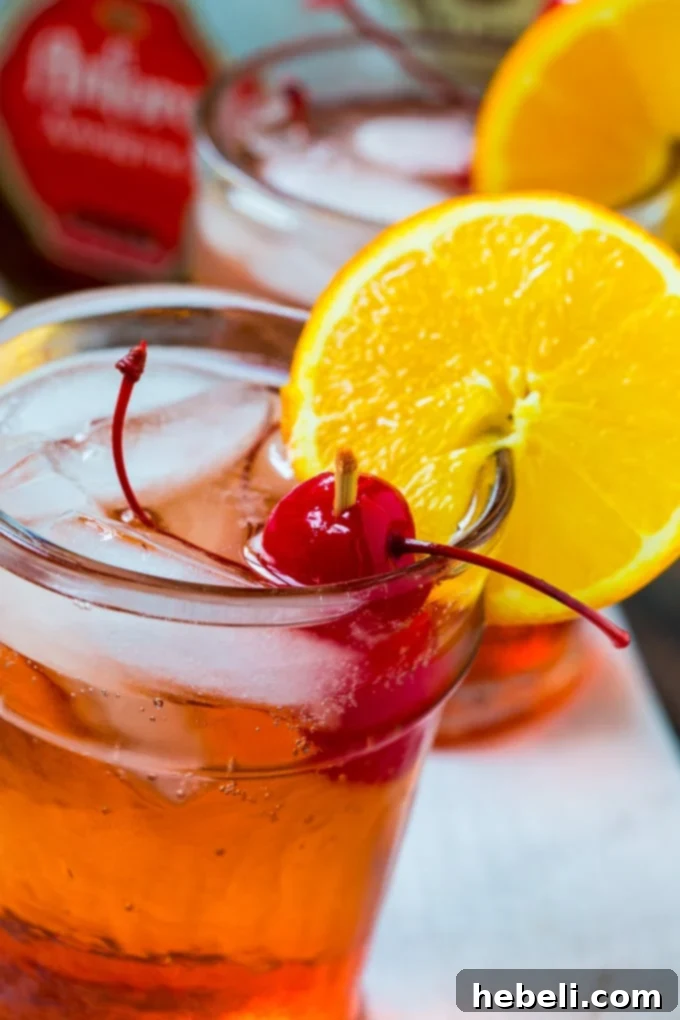 Two glasses of Bourbon Amaretto Cocktail ready to be served, garnished with orange and cherries