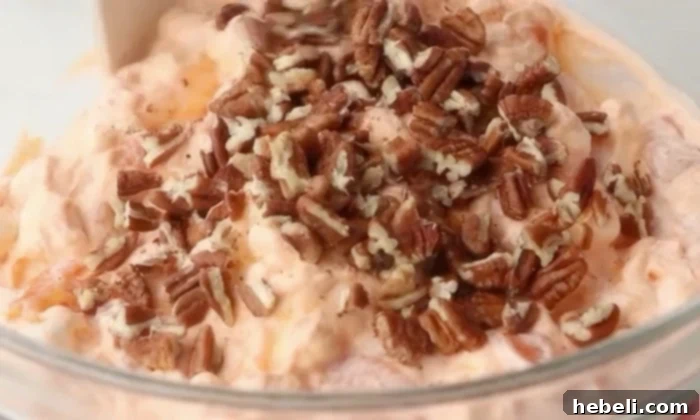 Golden Peach Ambrosia 8 Chopped pecans being sprinkled into the chilled peach salad just before serving, adding a final touch of crunch.