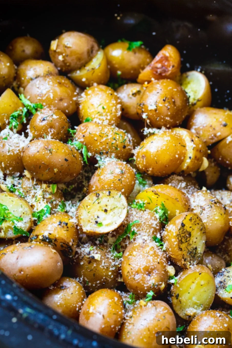 Potatoes in slow cooker sprinkled with fresh parsley and seasonings.