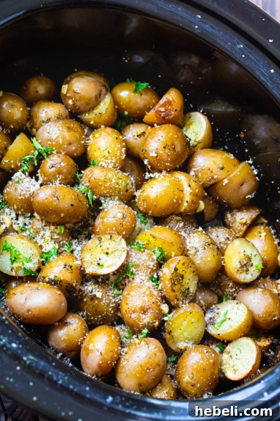 Cooked Slow Cooker Garlic Parmesan Potatoes in a black crock pot, ready to serve.