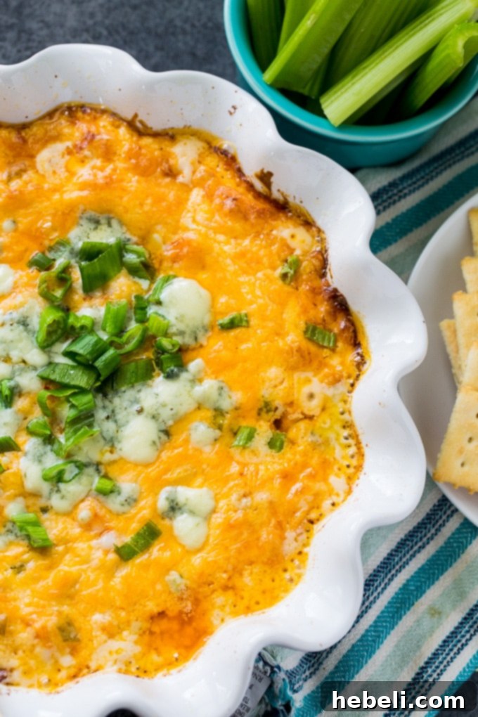 Hot and creamy Buffalo Shrimp Dip in a baking dish, garnished with green onions and blue cheese