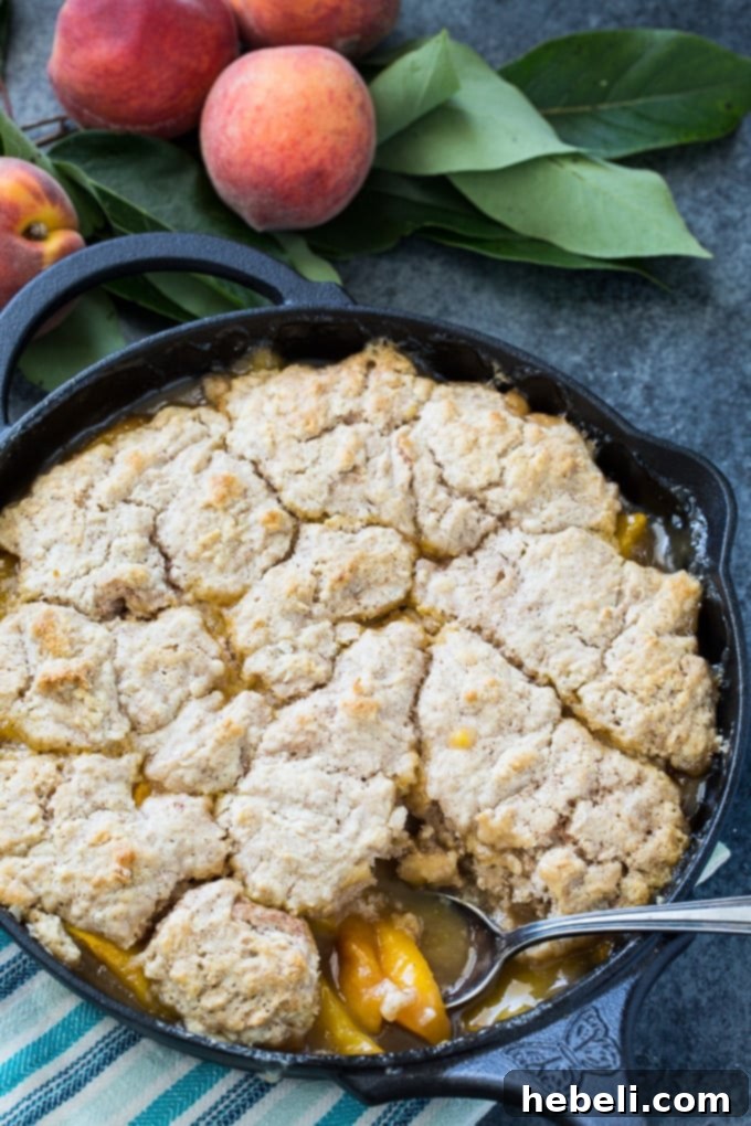 A delicious Skillet Bourbon Peach Cobbler with Cinnamon Sugar Dumpling, showcasing its golden crust and juicy peach filling.