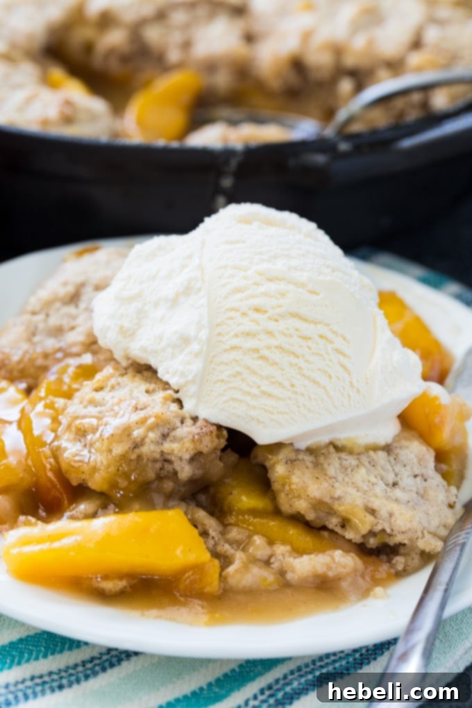 A top-down view of Skillet Bourbon Peach Cobbler with Cinnamon Sugar Dumpling, highlighting the golden crust and bountiful peach filling.