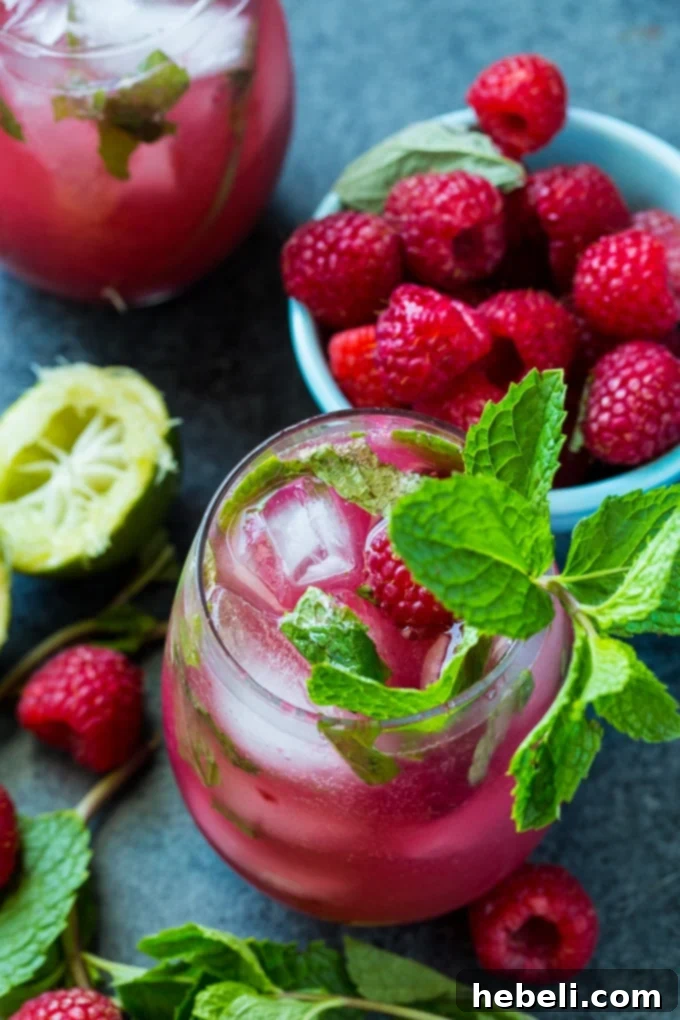 Easy Raspberry Mojito ingredients being muddled in a glass.