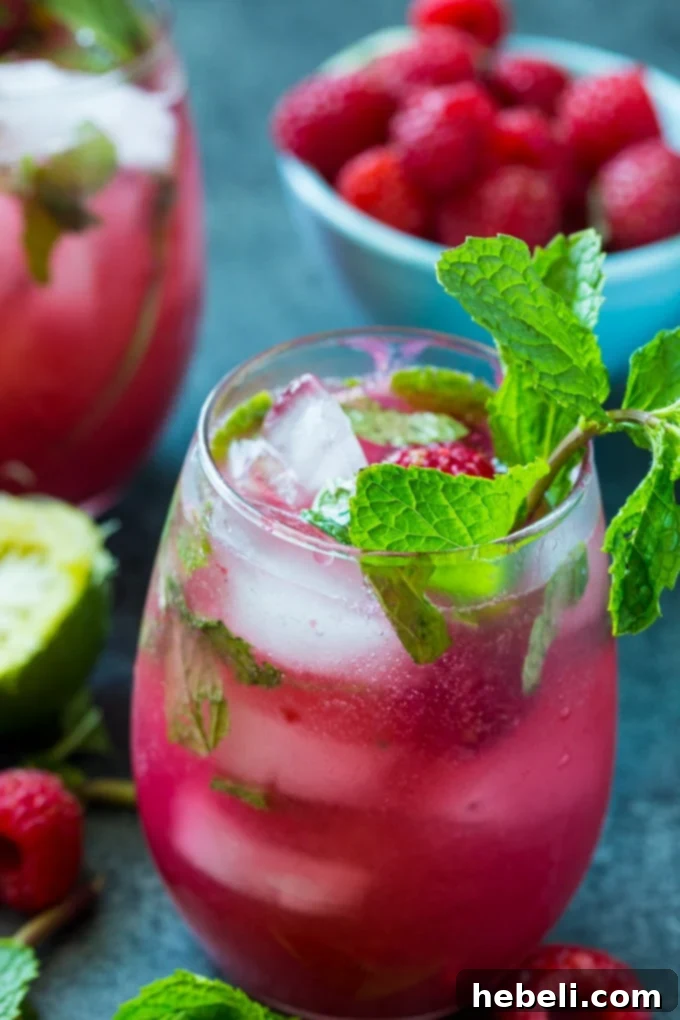 Easy Raspberry Mojito in a tall glass with fresh mint and raspberries.