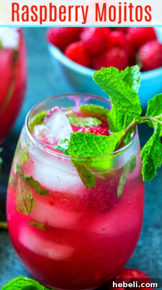 Close-up of a Mojito with raspberries in a glass with fresh mint garnish.