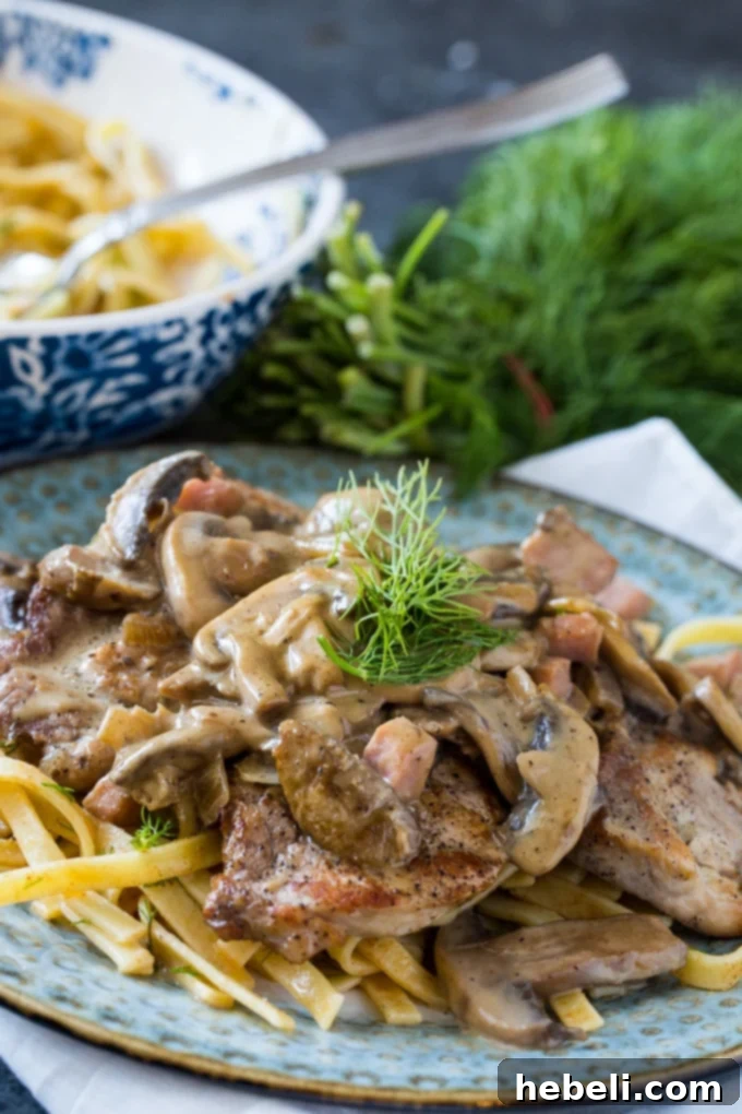 German Pork Cutlets served over dilled egg noodles with a side of green peas, ready to be enjoyed.