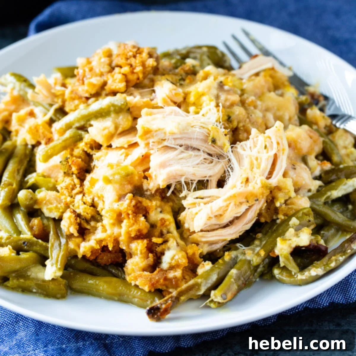 A serving of Crock Pot Chicken and Stuffing with Green Beans on a white plate, showcasing the golden stuffing, tender chicken, and vibrant green beans.