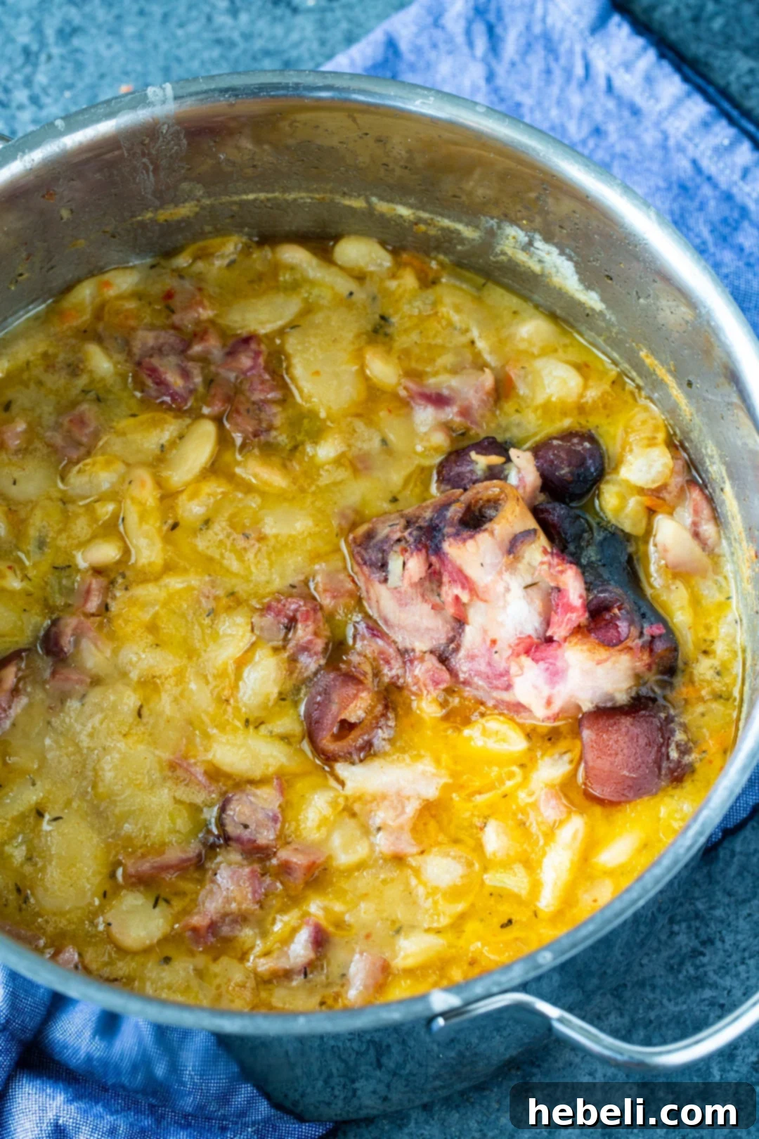 Smoked ham hocks and butter beans simmering in a large Dutch oven, releasing their rich, savory flavors into the broth.