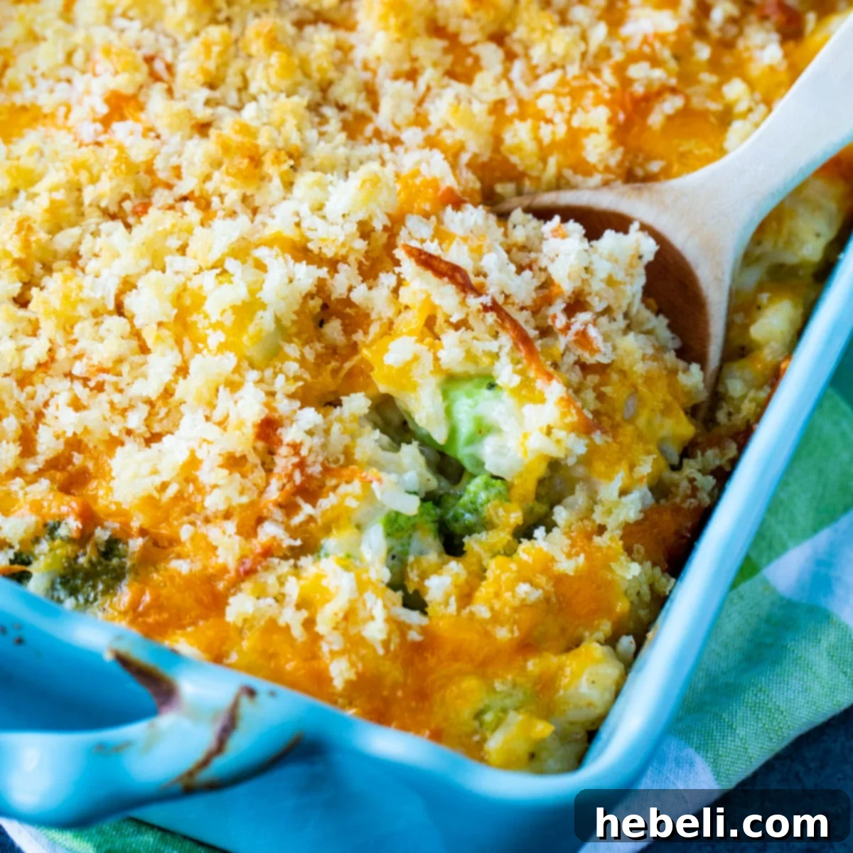 Ultimate Cheesy Broccoli and Rice Casserole 2 Spoon scooping a generous portion of warm, golden Cheesy Broccoli and Rice Casserole from a baking dish.