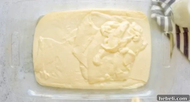 Smooth cake batter poured into a 9x13 inch baking pan, ready for the oven.