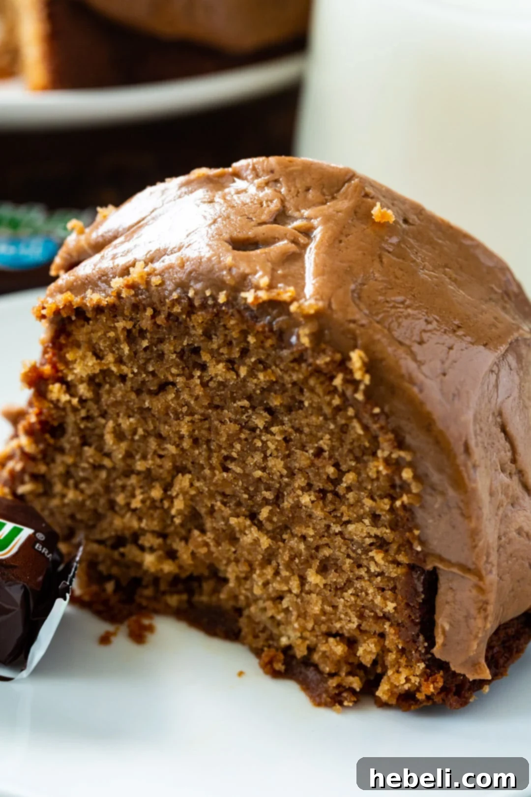 A close-up shot of a single slice of Milky Way Pound Cake, emphasizing the smooth, glossy frosting and the dense, moist texture of the cake.