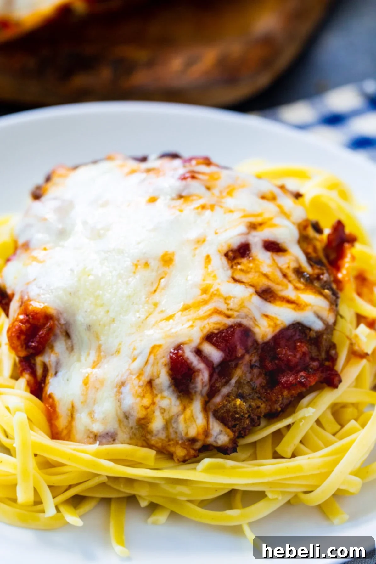 Close-up of Italian Cubed Beef, perfectly breaded and cheese-covered, nestled on a bed of spaghetti.