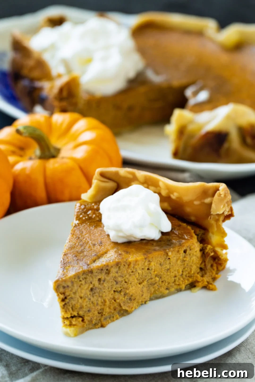A whole, beautifully baked Crock Pot Pumpkin Pie resting on a pristine white serving platter. The pie has a smooth, golden-orange surface and a perfectly crimped crust, showcasing its readiness for serving.