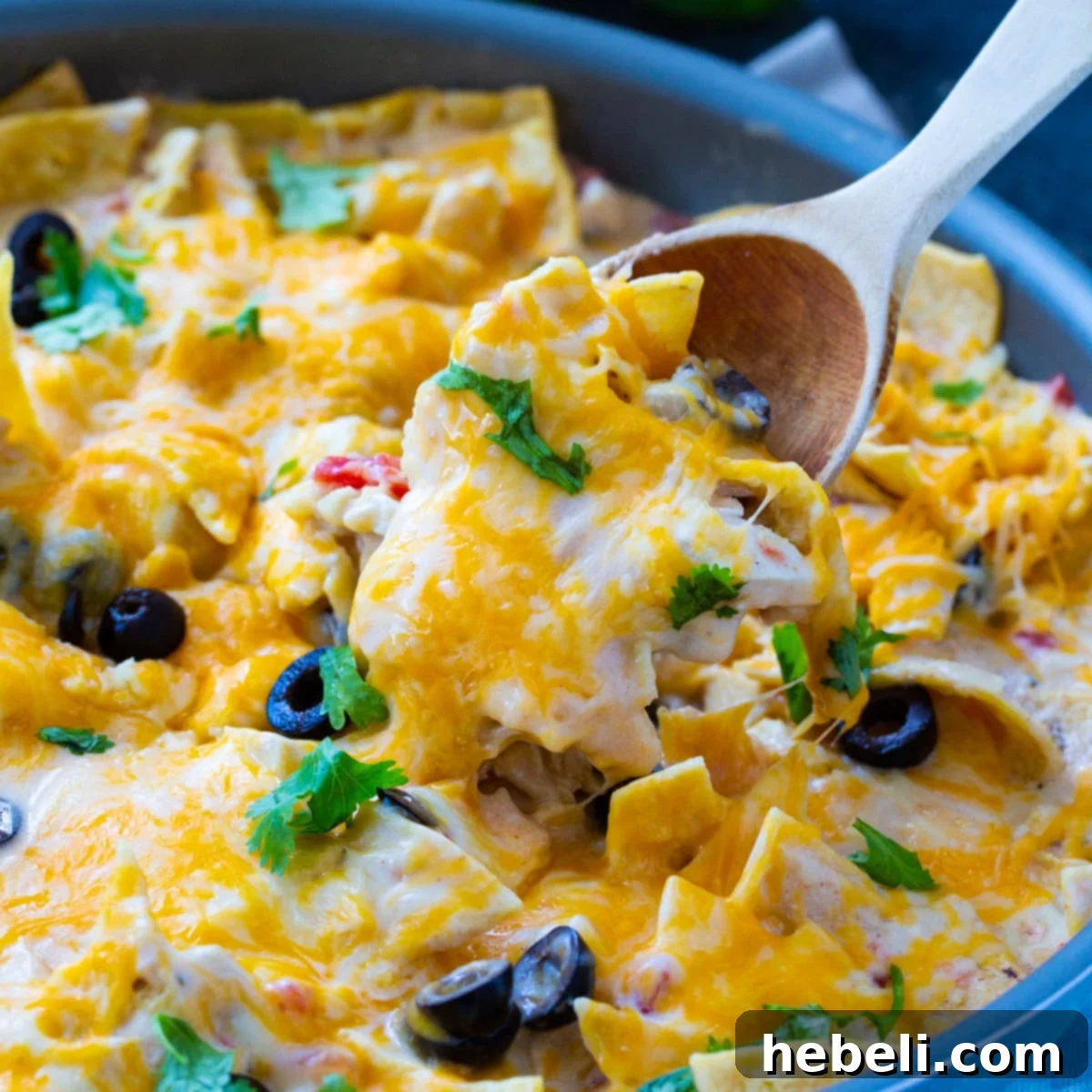 Delicious One Pot Creamy Chicken Enchilada Skillet in a cast iron skillet, with a spoon scooping out a serving.