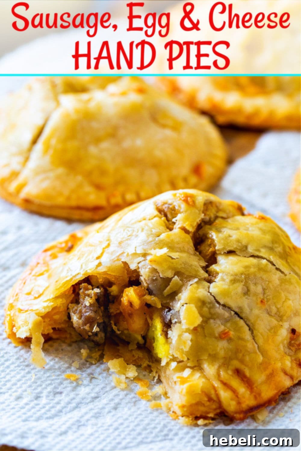 Multiple baked Sausage, Egg, and Cheese Hand Pies arranged on a wooden board, showcasing their golden-brown crust and inviting texture.