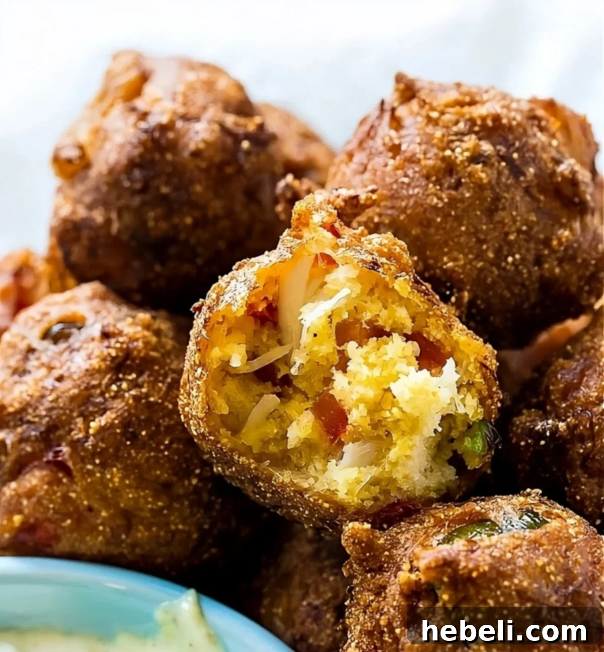 Golden Crab Bites 2 Piles of golden brown, crispy Crab Hush Puppies on a serving plate, ready to be enjoyed with a dipping sauce.
