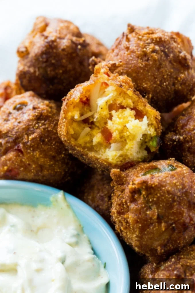 Golden Crab Bites 4 A close-up shot of several Crab Hush Puppies piled on a plate, garnished with fresh parsley and ready to be served.