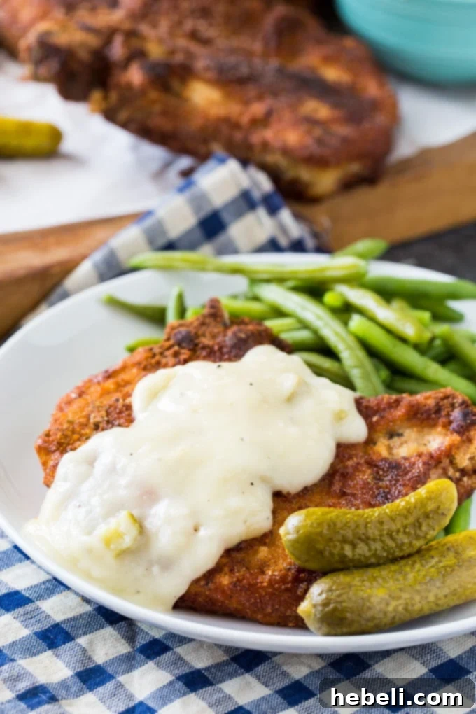 Tangy Pickle Gravy Pork Chops 5 Pork chops being fried in a cast iron skillet
