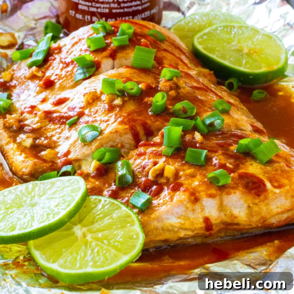 Firecracker Baked Salmon with lime slices on a baking sheet, showcasing a perfect golden-brown glaze.