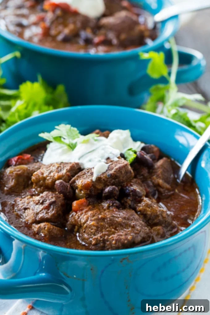 Close-up of Slow Cooker Brisket Chili, rich in color, with tender brisket pieces and black beans, ready to be topped.