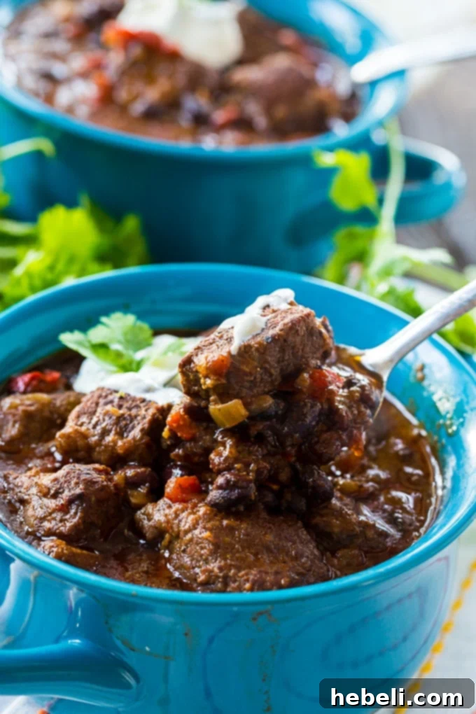 Overhead view of a hearty bowl of Slow Cooker Brisket Chili with a generous topping of lime sour cream and fresh cilantro.