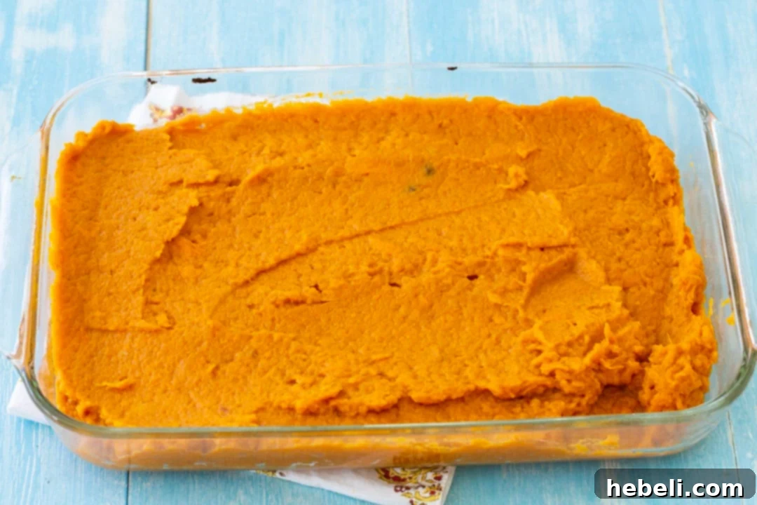 Smooth sweet potato mixture spread evenly in a baking dish, ready for toppings.