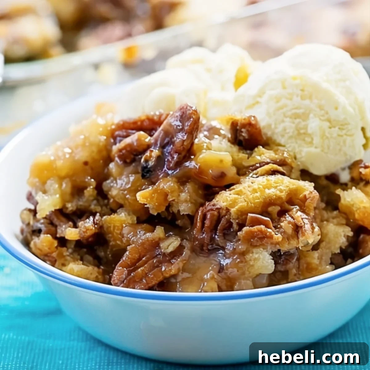 Decadent Pecan Pie Cobbler topped with a scoop of melting vanilla ice cream, ready to be enjoyed.